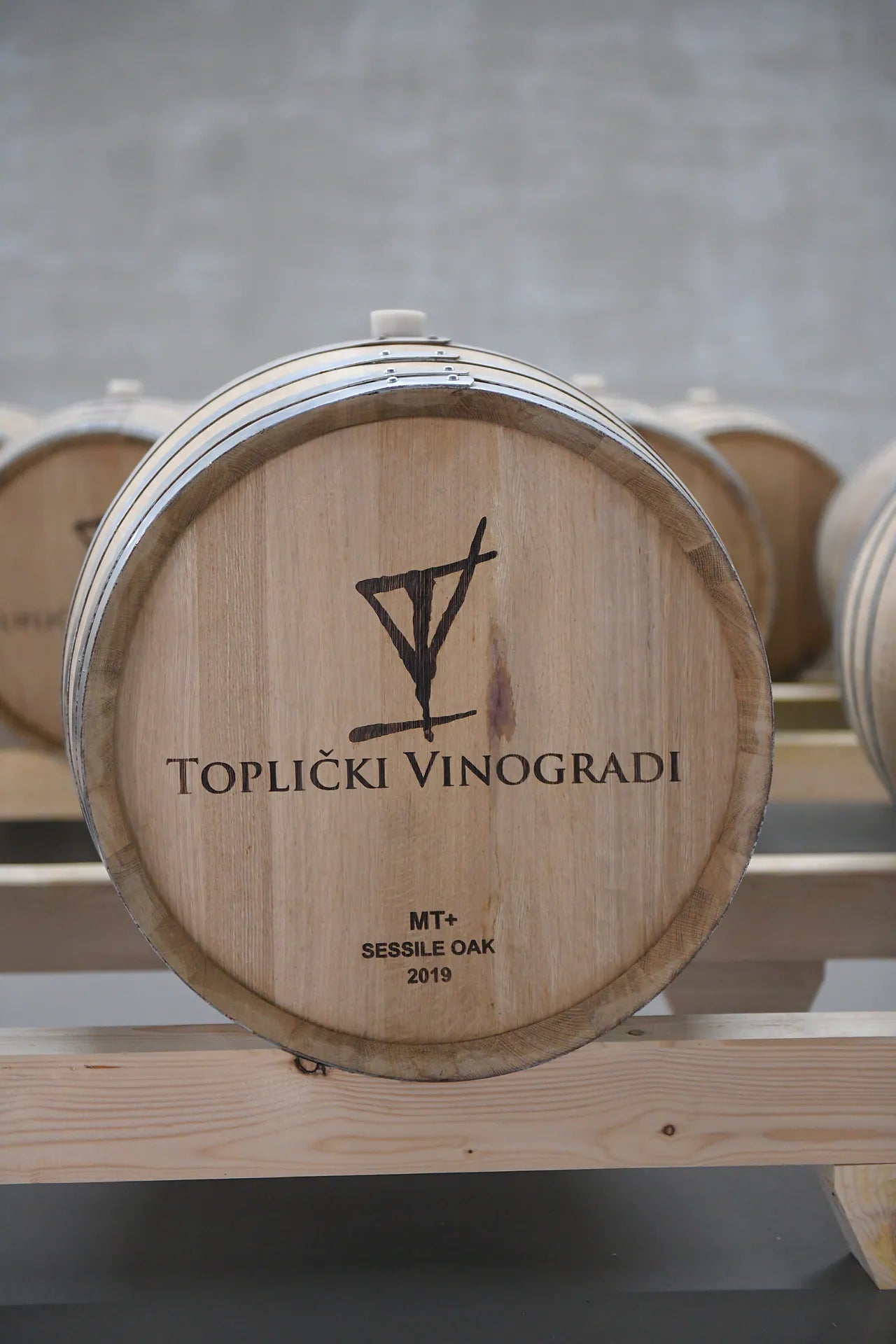 A barrel head in pale sessile oak, branded with the estate's goblet mark, the words Toplički Vinogradi, and the year 2019.