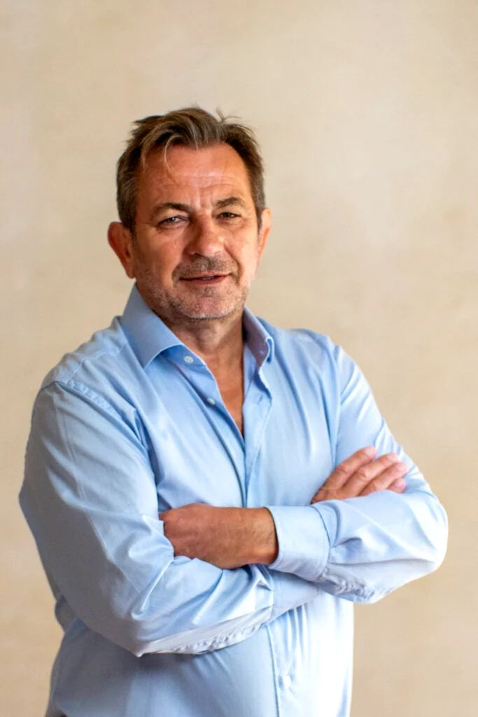 Milomir Kovačević, arms crossed in a pale blue shirt, against a plaster wall.